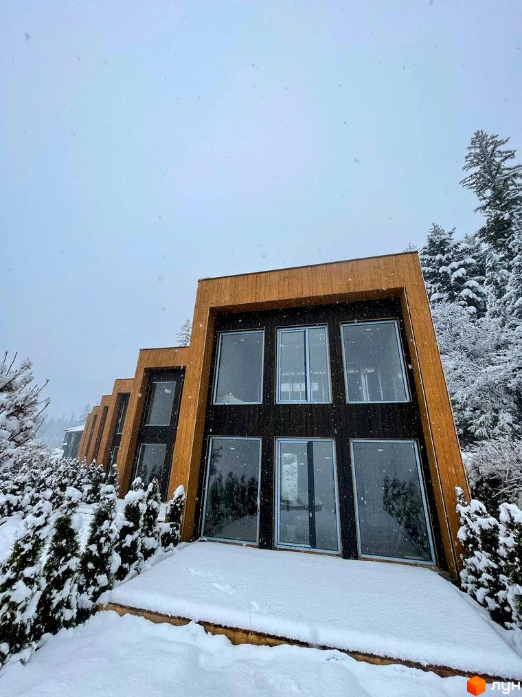 Котеджне містечко Агат Резорт & SPA: будинки з темними фасадами, дерев'яними рамами та великими вікнами. Засніжена територія з хвойними деревами.