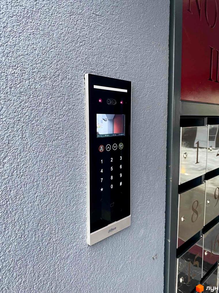 Домофон з екраном та кнопками на стіні біля поштових скриньок. ЖК Новатор має зручні рішення для безпеки мешканців.