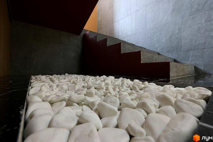 Сходи в Житловому комплексі Novator, оздоблені білим камінням. Вигляд на сходи з оздобленням з сірої плитки.