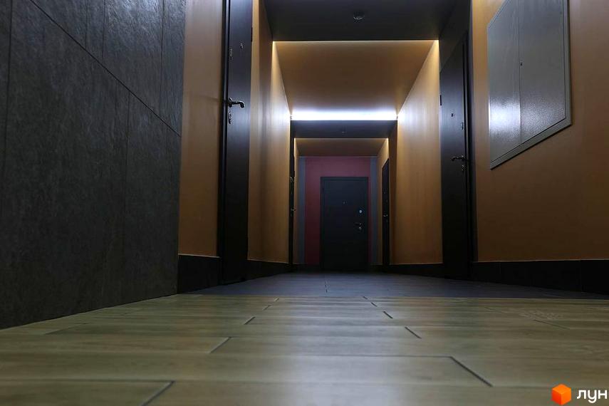 Фото коридору в Житловому комплексі Новатор. Інтер'єр коридору з дверима та освітленням, плитка на підлозі.