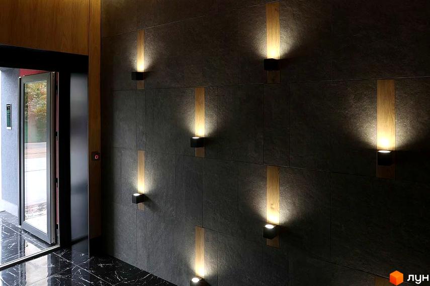 Інтер'єр вхідної групи Житлового комплексу Novator з освітленням на стінах та мармуровою підлогою.