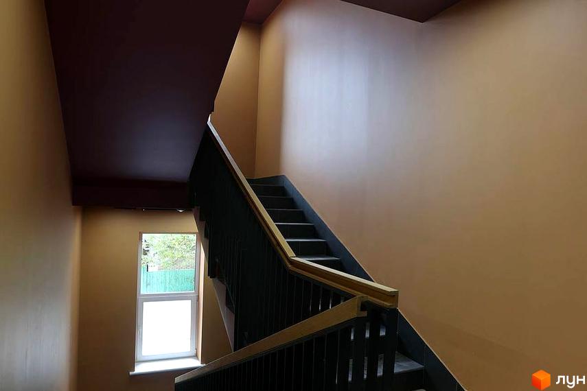 Сходи в під'їзді Житлового комплексу Новатор. Вигляд сходового майданчика з вікном та поручнями.