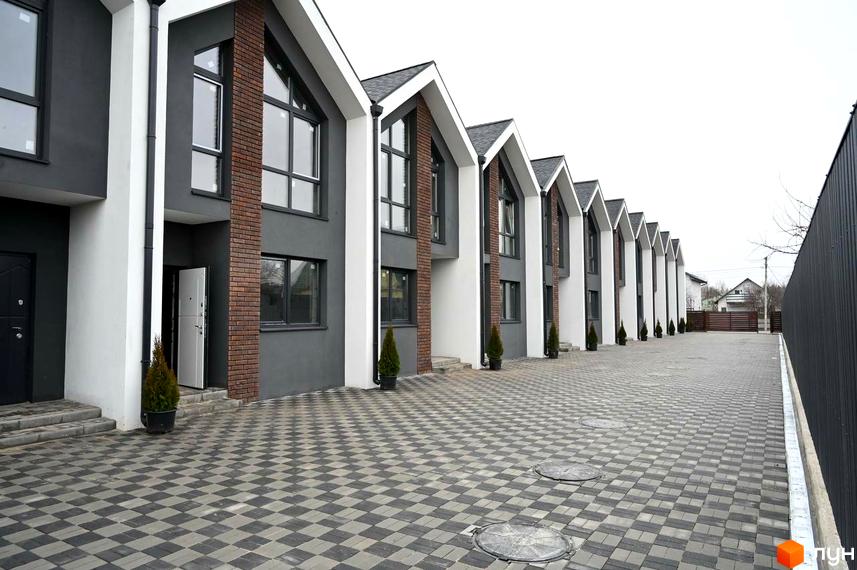 Ряд таунхаусів Dream Home з темно-сірими фасадами, білими акцентами та цегляними вставками. Перед будинками викладена бруківка, що веде до входів.