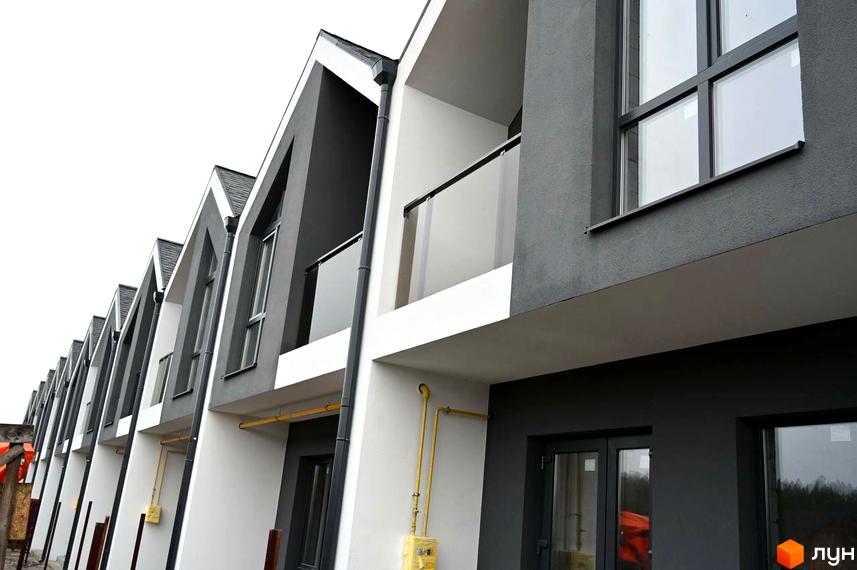 Таунхауси Dream Home: ряд будівель з темно-сірими та білими фасадами, гострими дахами та великими вікнами. Видно балкони та жовті газові труби.