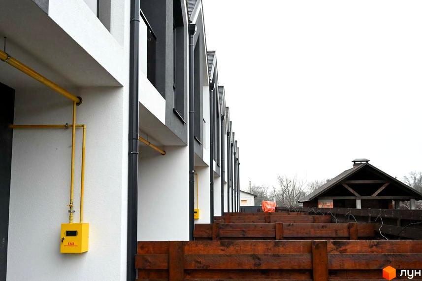 Зовнішній вигляд таунхаусів Dream Home з жовтими газовими трубами та дерев'яним парканом на прибудинковій території.