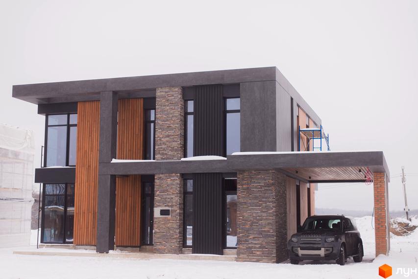 Котеджне містечко КМ 9 ЕЛЕМЕНТІВ. Двоповерховий будинок з дерев'яними та цегляними елементами фасаду, прибудинкова територія зі снігом та автомобілем.