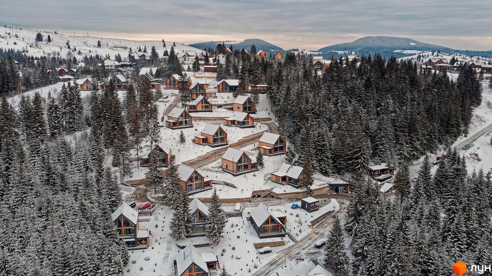 Зимовий пейзаж Котеджного містечка SKOGUR з дерев'яними котеджами, вкритими снігом, серед засніженого лісу.