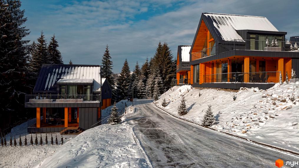 Зображення Котеджного містечка SKOGUR взимку. Двоповерхові будинки з дерев'яним оздобленням та засніженою територією навколо.