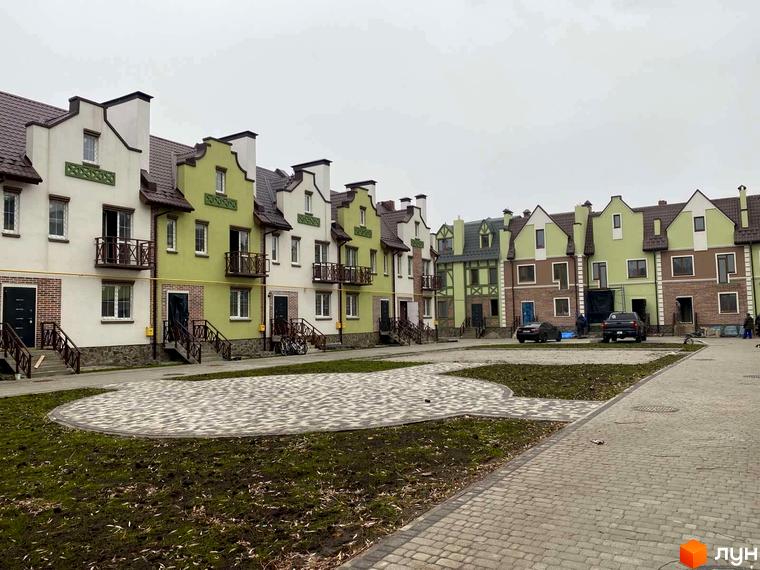 Таунхауси „Нова Конча-Заспа“ з різнокольоровими фасадами та балконами. Вид на забудову та бруковану прибудинкову територію.