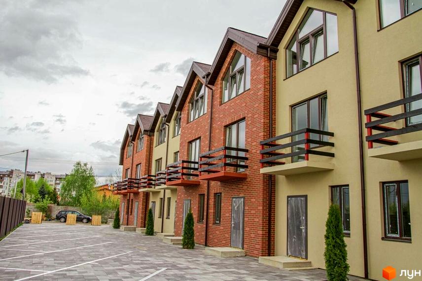 Ряд таунхаусів Modern House з цегляними фасадами та балконами. Перед будинками розташована бруківка, а поруч ростуть дерева.