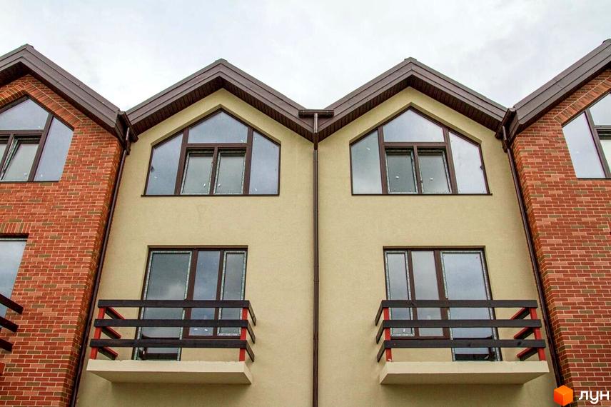 Фасад будинку Modern House з двосхилим дахом та панорамними вікнами. На фасаді є балкони з дерев'яними поручнями, поруч цегляна кладка.