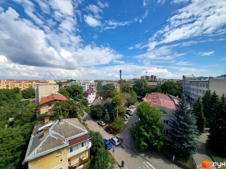 Вид на клубний будинок Kovcheg Residence з навколишніми будинками та зеленою зоною. Навколо будинку розташовані дерева та дороги.