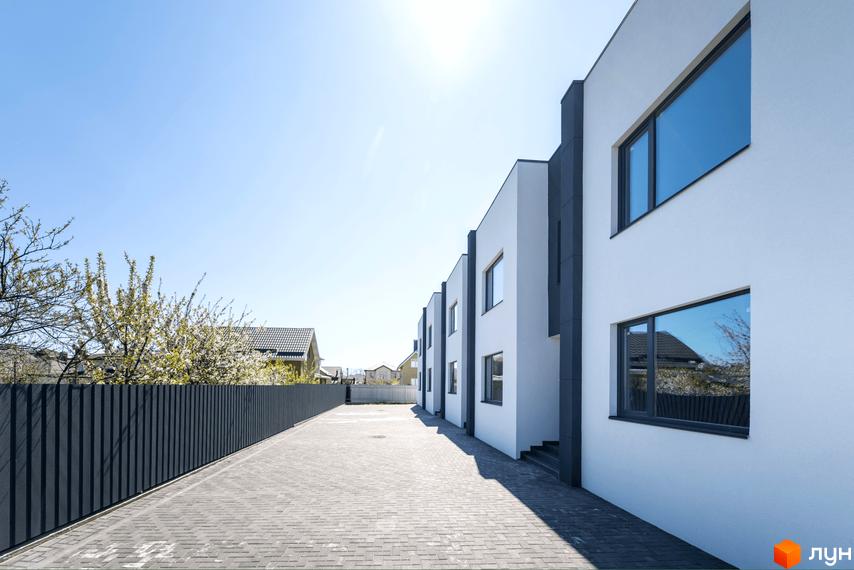 Зовнішній вигляд новобудови на вул. Полтавська, 15, з сірою огорожею та бруківкою.