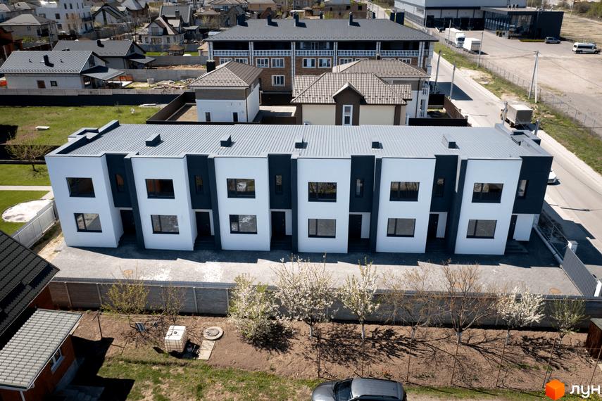 Новобудова на вул. Полтавська, 15 з білими фасадами та темними акцентами. На прибудинковій території розташовані дерева та паркан.