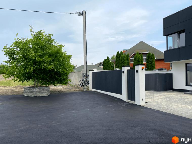 Новобудова на вулиці Райдужна, 18 з сірим парканом та зеленим деревом на прибудинковій території.