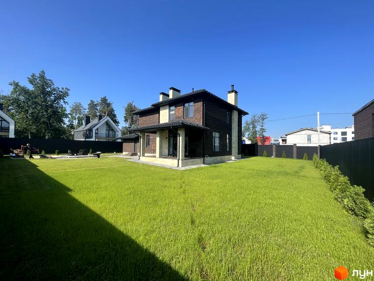 Котеджне містечко Spacious HOME. Зовнішній вигляд цегляного будинку з двома поверхами та камінами. Навколо будинку доглянутий зелений газон та огороджена територія.