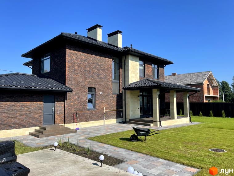 Котеджне містечко Spacious HOME: двоповерховий будинок з цегляним фасадом та чорною черепичною покрівлею, доглянутий газон та брукована доріжка.