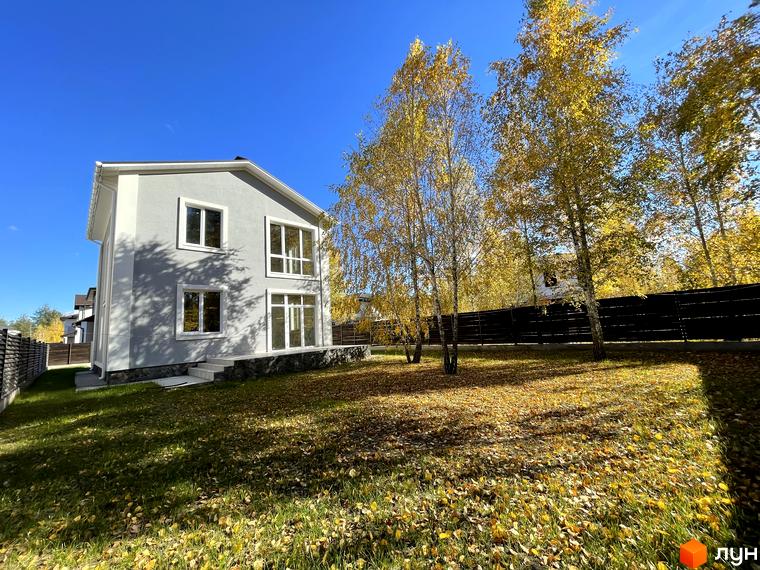 Котеджне містечко ForestK: сірий двоповерховий будинок з білими вікнами та дверима, оточений деревами з жовтим листям.