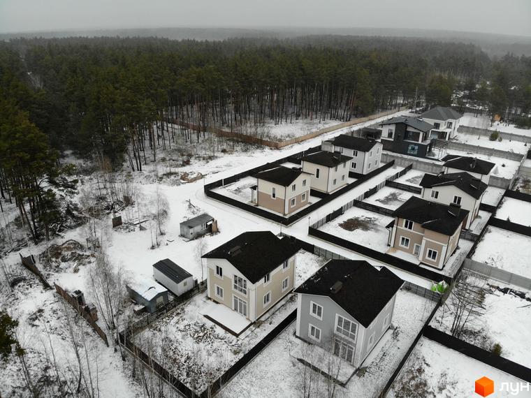 Котеджне містечко ForestK: двоповерхові будинки з темними дахами та світлими фасадами на тлі зимового лісу. Прибудинкова територія огороджена парканом, на ділянках лежить сніг.