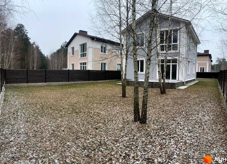 Зовнішній вигляд будинків у КМ ForestK з прибудинковою територією, покритою опалим листям. Комплекс розташований серед дерев.