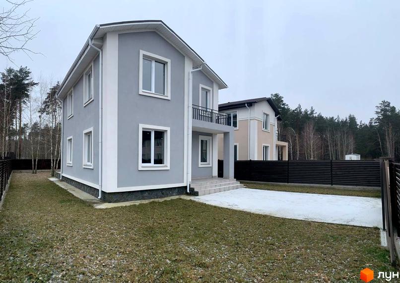 Зовнішній вигляд сірого двоповерхового будинку з білими вікнами та балконом у КМ ForestK. Навколо будинку доглянута прибудинкова територія з газоном та парканом.