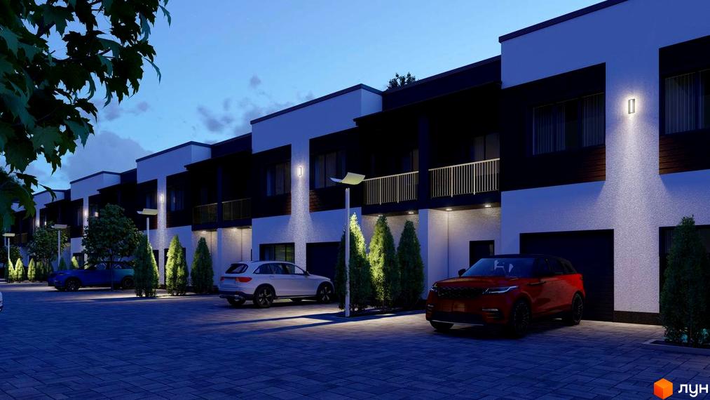 Ряд таунхаусів Dream Town з темними фасадами та світлими акцентами, освітлених ввечері. На території бруківка, дерева та паркувальні місця.