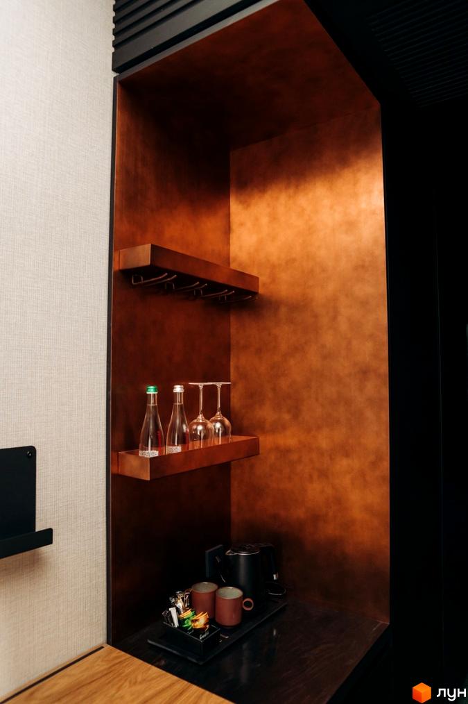 Інтер'єр апартаментів LEV RESORT HOTEL: ніша з полицями, скляним посудом, пляшками та чайником. Стіни оздоблені під мідь.