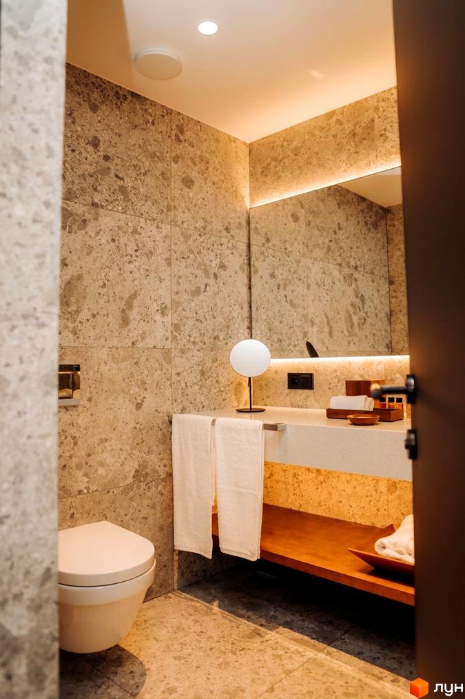 Інтер'єр ванної кімнати в LEV RESORT HOTEL. Світла плитка на стінах та підлозі, біла сантехніка, дерев'яні елементи декору.