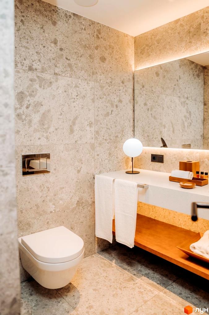 Інтер'єр ванної кімнати в апарт-комплексі LEV RESORT HOTEL. Світла плитка, біла сантехніка та дерев'яні елементи декору створюють атмосферу спокою.