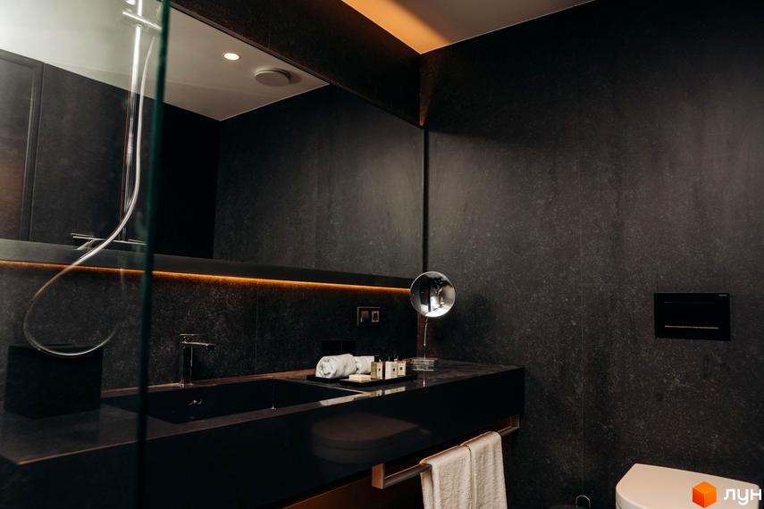 Інтер'єр ванної кімнати в апарт-комплексі LEV RESORT HOTEL. Чорні стіни, велике дзеркало, раковина з темного каменю, рушники.