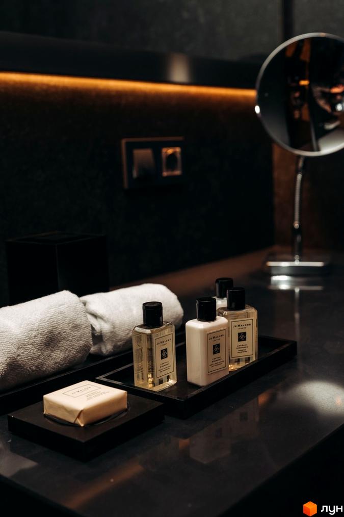 Інтер'єр ванної кімнати в апарт-готелі LEV RESORT HOTEL з косметичними засобами та рушниками на стільниці.