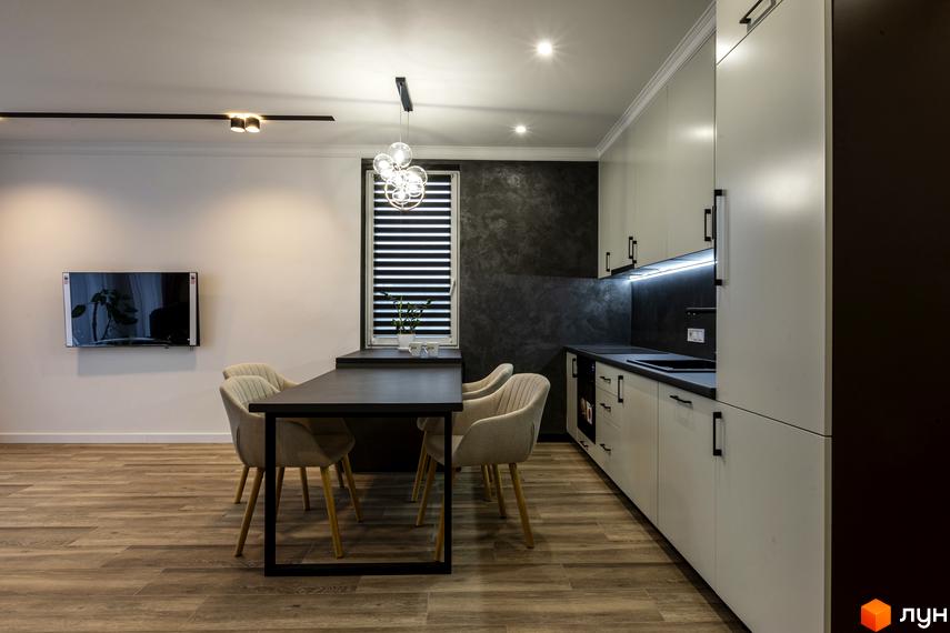Інтер'єр кухні-вітальні у ЖК Струмочок 2 з обідньою зоною та сучасною кухонною технікою. Простора вітальня зона з телевізором.