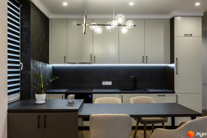 Сучасна кухня з сірими фасадами, острівцем та вбудованою технікою. На стільниці стоїть вазон із зеленою рослиною та дві чашки.