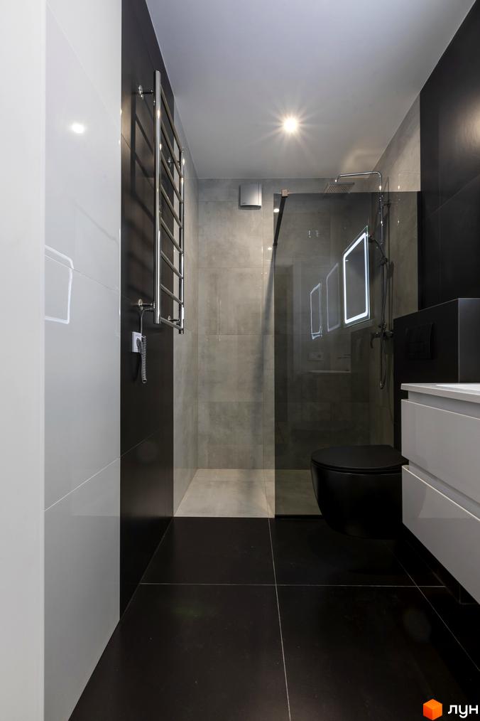 Сучасний дизайн ванної кімнати з чорною сантехнікою та сірою плиткою. Велике дзеркало з підсвіткою додає простору.