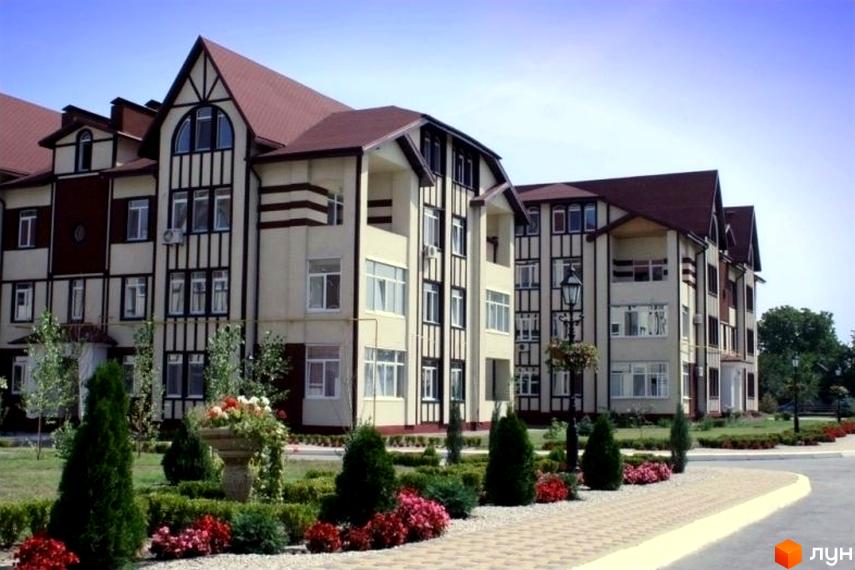 Житловий комплекс Ренесанс з фасадом у світлих тонах та озелененою прибудинковою територією, оформленою квітами та зеленими насадженнями.