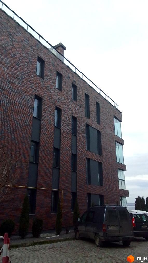 Фасад цегляного житлового комплексу по вул. Над Ставом, 4, з великими вікнами та прибудинковою територією з деревами та автомобілями.