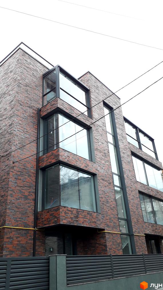 Фасад житлового комплексу на вулиці Над Ставом, 4, з цегляним оздобленням та великими вікнами. На передньому плані - сучасний паркан.