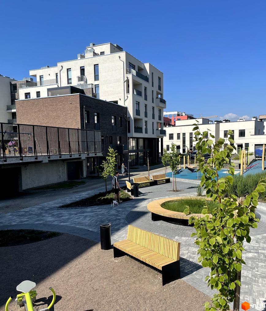 Житловий комплекс Villa Magnolia Spring: білі та цегляні фасади будинків, внутрішній двір з лавками та дитячим майданчиком. Сучасна архітектура та комфортна прибудинкова територія.