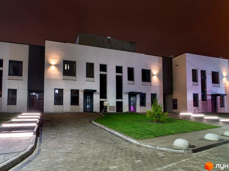 Зовнішній вигляд новобудови ЖК Villa Magnolia з підсвіченими сходами та доглянутою прибудинковою територією. Сучасна архітектура та освітлення створюють затишну атмосферу.