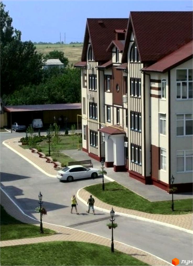 Зовнішній вигляд житлового комплексу ЖК Ренесанс з прибудинковою територією, де видно зелені насадження та пішохідні доріжки.