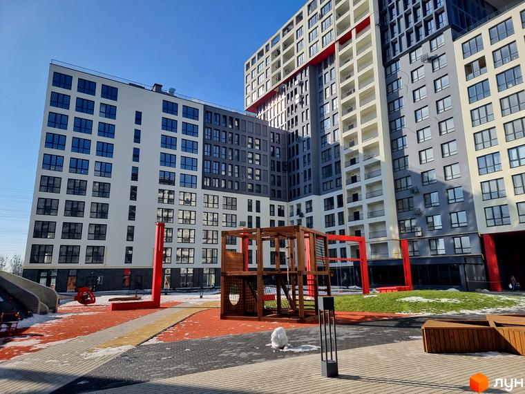 Зображення фасаду та подвір'я Житлового комплексу Вільне Місто. На території розташовані дитячий майданчик та зелені насадження.