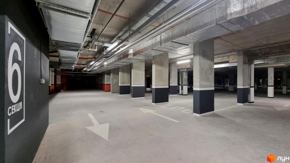 Підземний паркінг Житлового комплексу Вільне Місто з бетонними опорами, чіткою розміткою та відкритими інженерними комунікаціями на стелі.