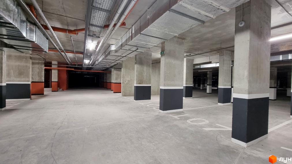 Просторий підземний паркінг Житлового комплексу Вільне Місто з бетонними опорами, системою вентиляції та розміткою паркувальних місць.