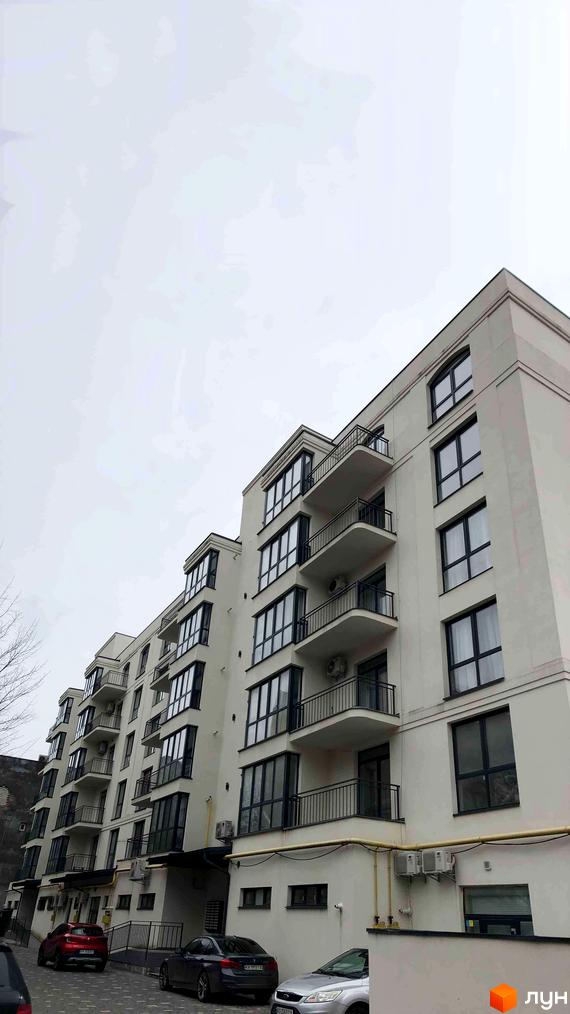 Фасад житлового комплексу на вулиці Капушанська, 34, з балконами та великими вікнами. Біля будинку розташовані автомобілі.