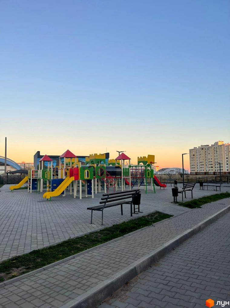 Житловий комплекс Kokos Avenue з дитячим майданчиком та лавками. Вигляд на будівлю та облаштовану прибудинкову територію.