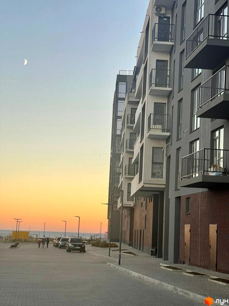 Зовнішній вигляд будинку в Житловому комплексі Kokos Avenue. Прибудинкова територія з тротуаром, освітленням та автомобілями.