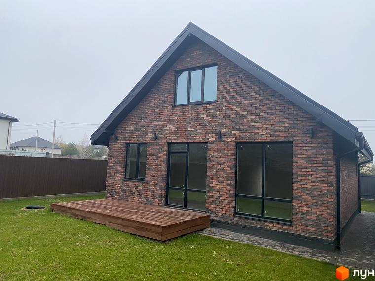 Котеджне містечко КМ Одноповерховий Київ - Віта-Поштова. Цегляний будинок з великими вікнами та дерев'яною терасою на зеленій ділянці.