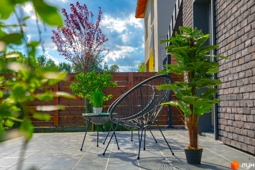 Котеджне містечко BritanHouse: сучасний фасад будівлі та затишна прибудинкова територія з місцем для відпочинку.