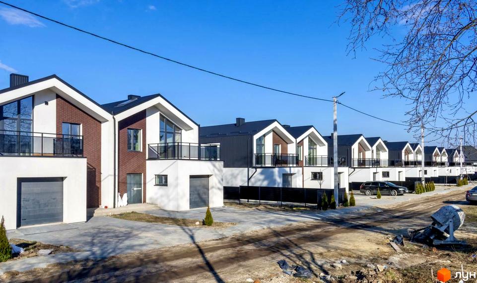 Новобудова Дуплекси „Черешня“: сучасні дуплекси з гаражами та балконами на тлі чистого неба та зелених дерев. Прибудинкова територія з доглянутими газонами та дорогою.