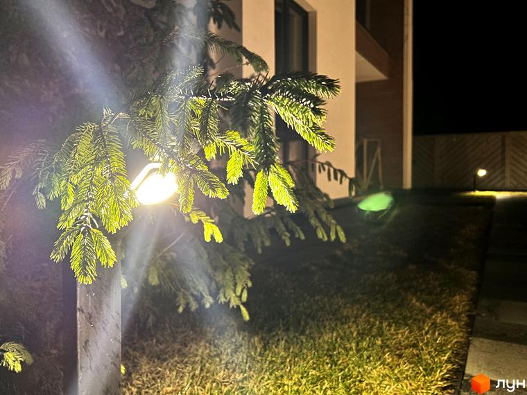 Котеджне містечко КМ Hill Park. Нічне освітлення фасаду будинку та прибудинкової території з ялиною.